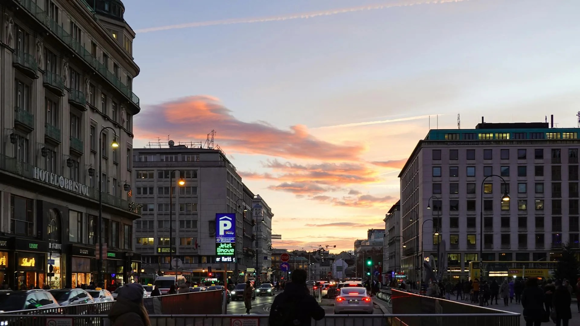 Busy Vienna street at sunset with people and cars